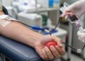 Primer plano de una donación de sangre con brazo del donante y personal sanitario sin rostros visibles
