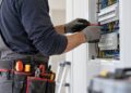 Electricista trabajando con herramientas en un cuadro eléctrico, sin mostrar el rostro